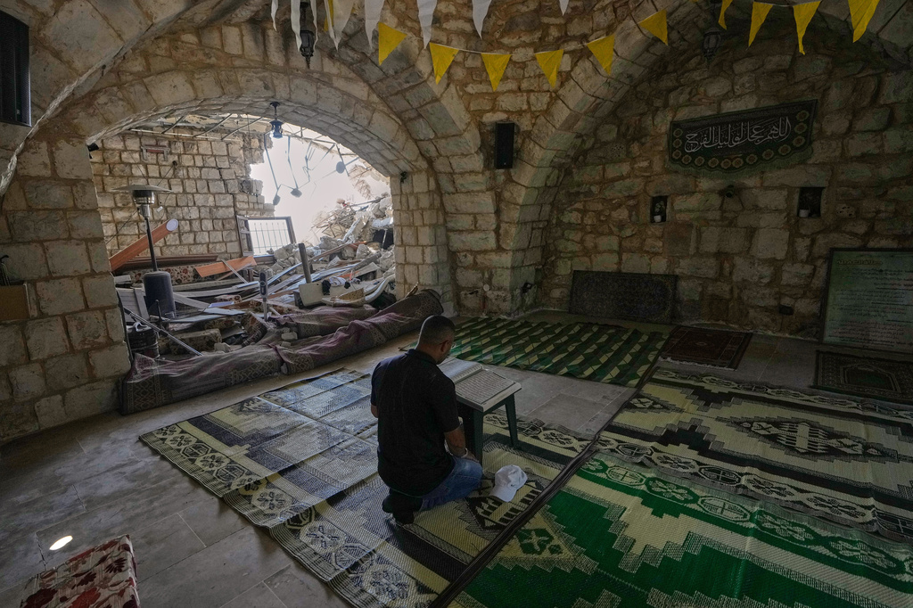 A Lebanese man reads a copy of the Quran inside a damaged house in the village of Zawtar al-Gharbieh, south Lebanon, Wednesday, Aug. 5, 2026. (AP Photo/Mohammed Zaatari)