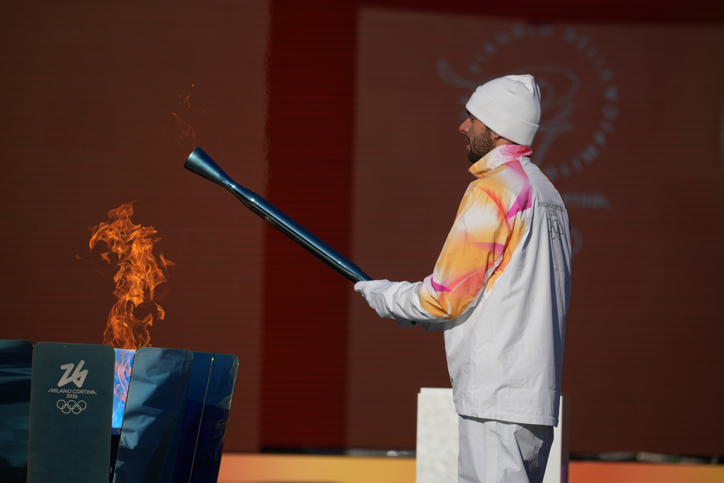 Italian swimmer Gregorio Paltrinieri lights the 2026 Milan Cortina Winter Olympics torch in Rome as it begins its journey through Italy, Saturday, Dec. 6, 2025, a journey that will conclude in Milan in February 2026. (AP Photo/Andrew Medichini)