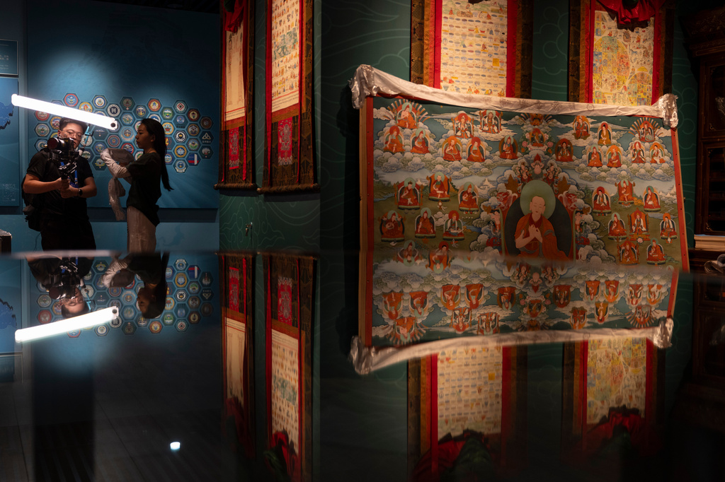 Journalists work near Thangka displayed at a showroom detailing the development of traditional Tibetan medicine at the Xizang Autonomous Region Hospital of Tibetan Medicine in Lhasa, in western China's Tibet Autonomous Region on Wednesday, July 22, 2026 as seen during a government organized visit for foreign journalists. (AP Photo/Ng Han Guan)