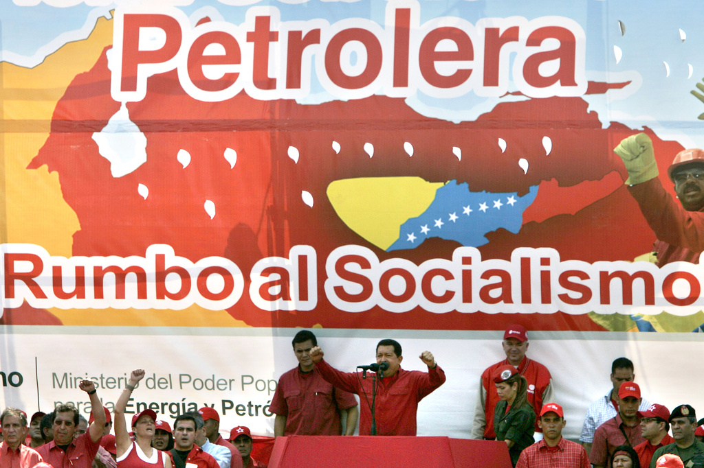 FILE - Venezuela's President Hugo Chavez, center, delivers a speech in front of a banner that reads in Spanish "Oil Company on its way to socialism", to oil workers in Barcelona, Venezuela, Tuesday, May 1, 2007. (AP Photo/Fernando Llano, File)