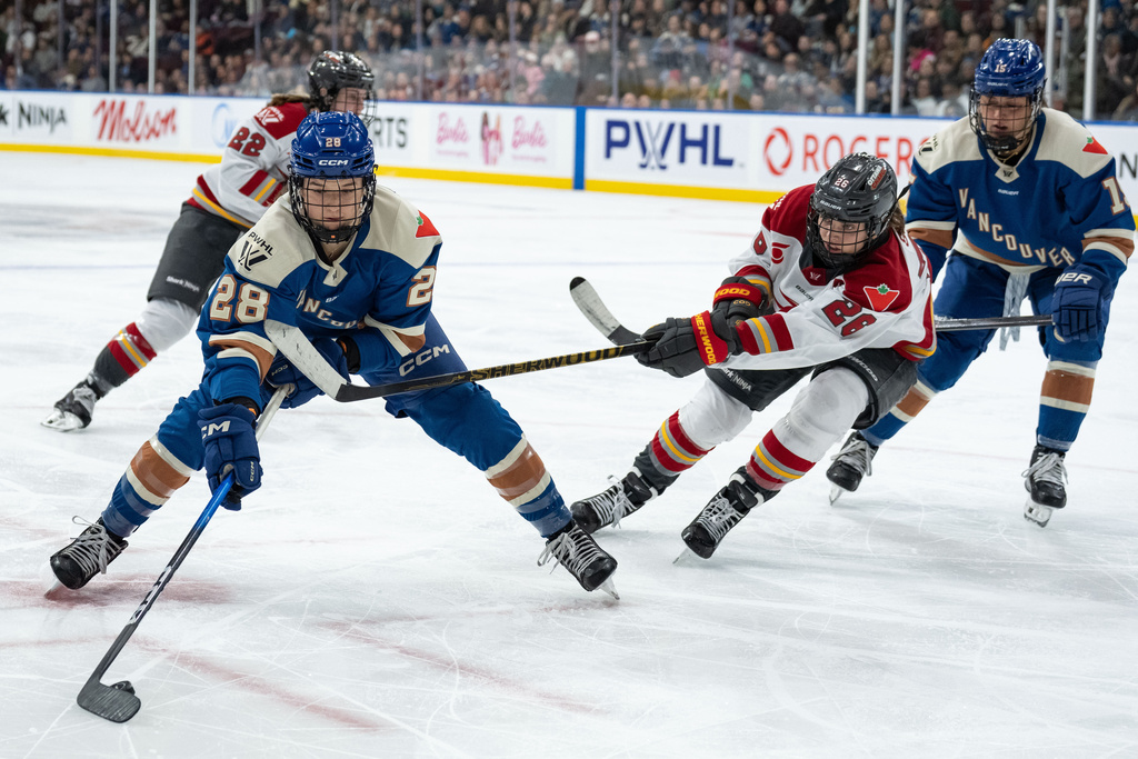 Vancouver Goldeneyes' Nina Jobst-Smith (28) skates with the puck as Ottawa Charge's Emily Clark (26) defends and Vancouver's Gabby Rosenthal (15) watches during the third period of a PWHL hockey game in Vancouver, British Columbia, Saturday, March 14, 2026. (Ethan Cairns/The Canadian Press via AP)