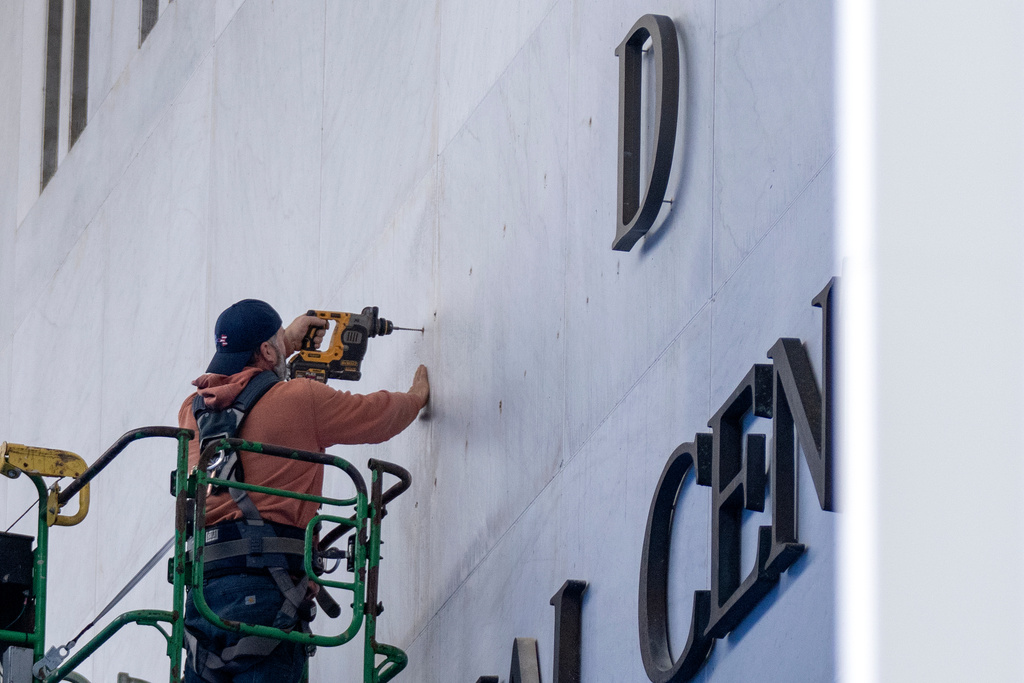 A worker drills holes near letters being installed above the signage on the Kennedy Center on Friday, Dec. 19, 2025, in Washington. (AP Photo/Mark Schiefelbein)