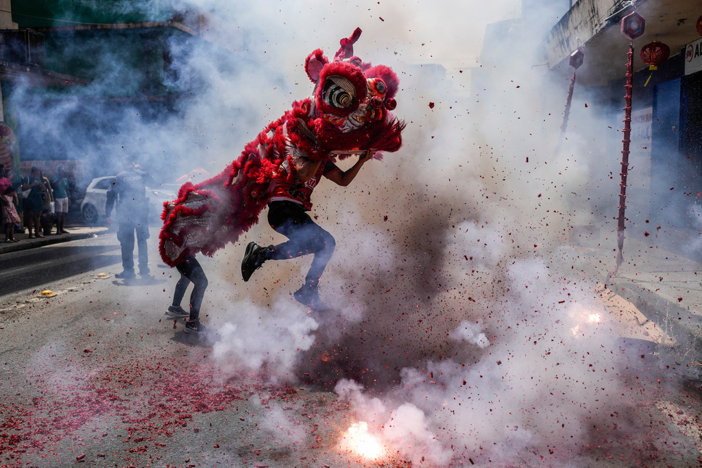 People perform a lion dance as fireworks explode during Lunar New Year celebrations in Panama City, Wednesday, Feb. 18, 2026. (AP Photo/Matias Delacroix)