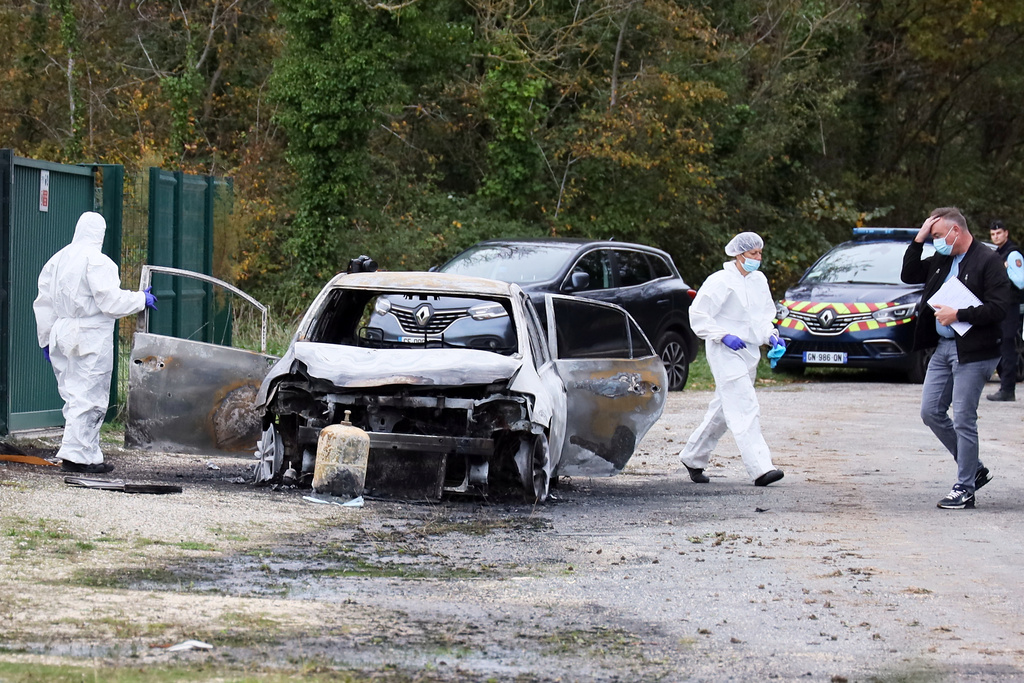 Investigators inspect the burned car after a motorist deliberately rammed pedestrians and cyclists across two neighbouring towns on the Ile d'Oleron, off the Atlantic coast, injuring people before being detained by gendarmes, Wednesday, Nov. 5, 2025. (AP Photo/Yohan Bonnet)