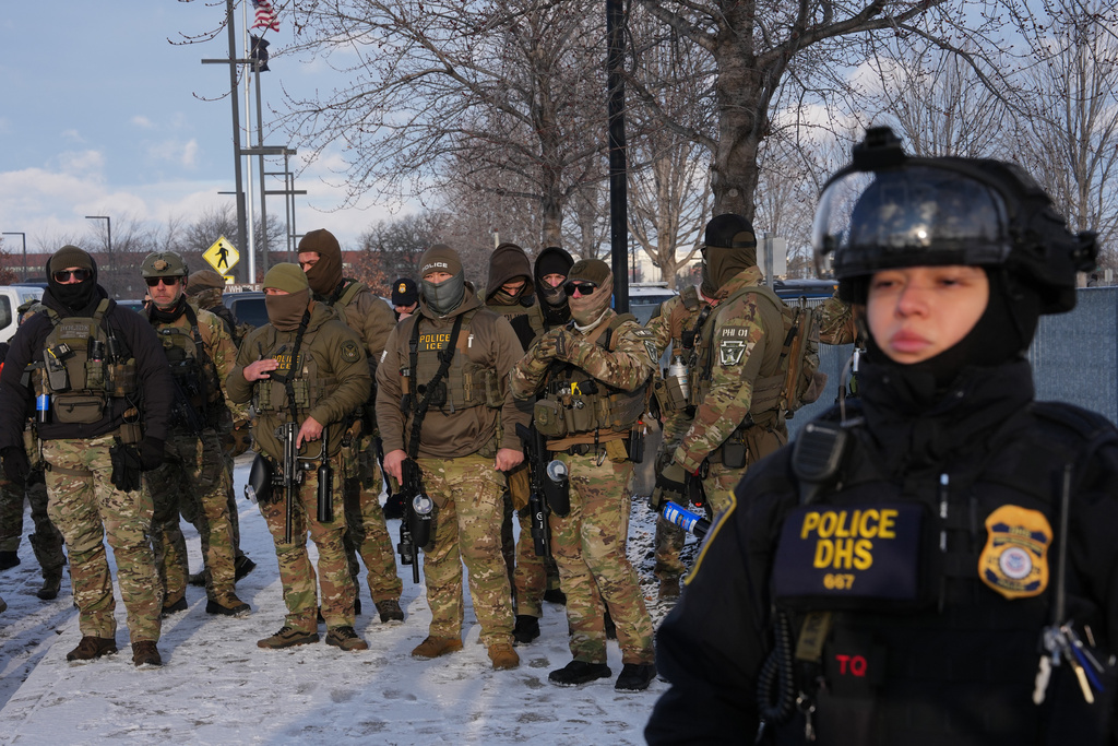 Federal agents stand outside the Bishop Henry Whipple Federal Building as protesters gather in Minneapolis, Saturday, Jan. 10, 2026. (AP Photo/Adam Gray)