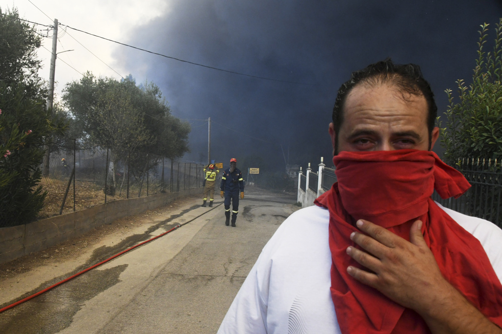 Black smoke covers the sky during a wildfire in the village of Moiraiika near Patras city, western Greece, Tuesday, Aug. 12, 2025. (AP Photo/Giannis Androutsopoulos)