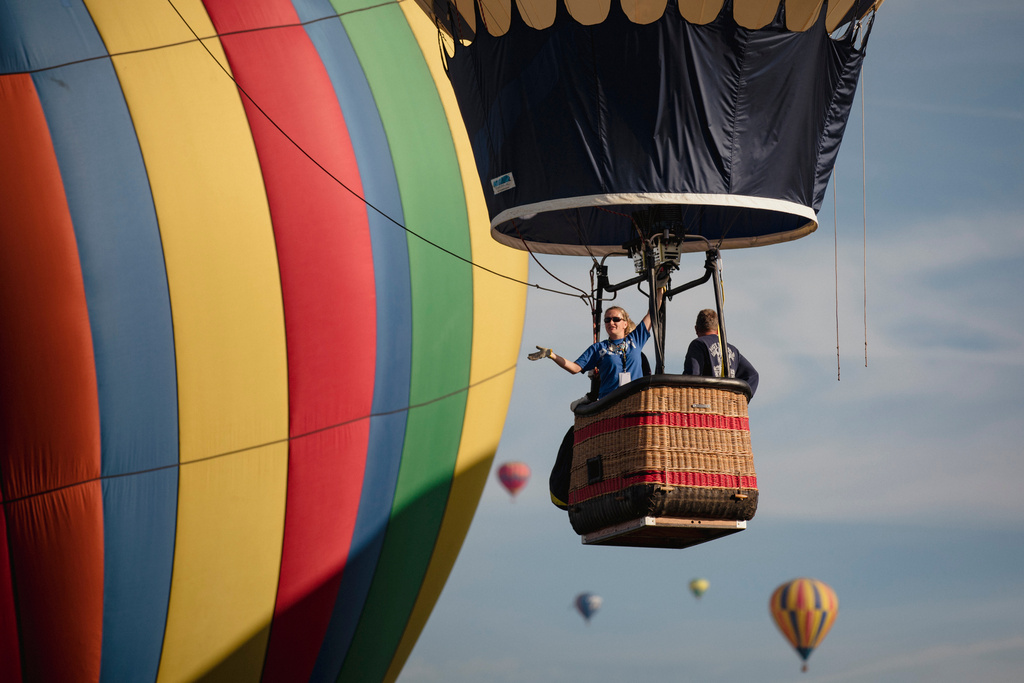 FILE - A balloon crew waves to the crowd over Albuquerque, N.M., on the second day of the Balloon Fiesta Oct. 3, 2021. (Adria Malcolm/The Albuquerque Journal via AP, File)