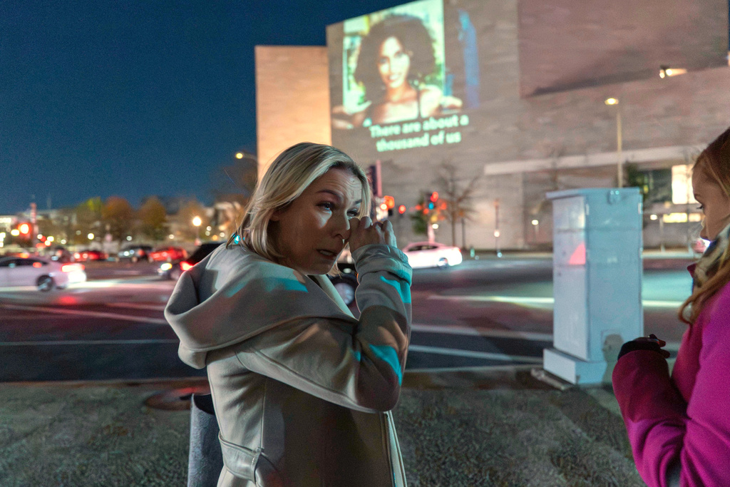Danielle Bensky wipes a tear as a World Without Exploitation projection is seen on the wall of the National Gallery of Art calling on Congress to vote yes on the Epstein files transparency act in Washington, Monday, Nov. 17, 2025. (AP Photo/Jose Luis Magana)