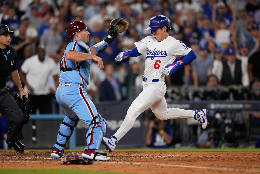 Los Angeles Dodgers' Hyeseong Kim scores past Philadelphia Phillies catcher J.T. Realmuto on a ground ball by Andy Pages and a throwing error by Phillies pitcher Orion Kerkering during the eleventh inning in Game 4 of baseball's National League Division Series Thursday, Oct. 9, 2025, in Los Angeles. (AP Photo/Mark J. Terrill)