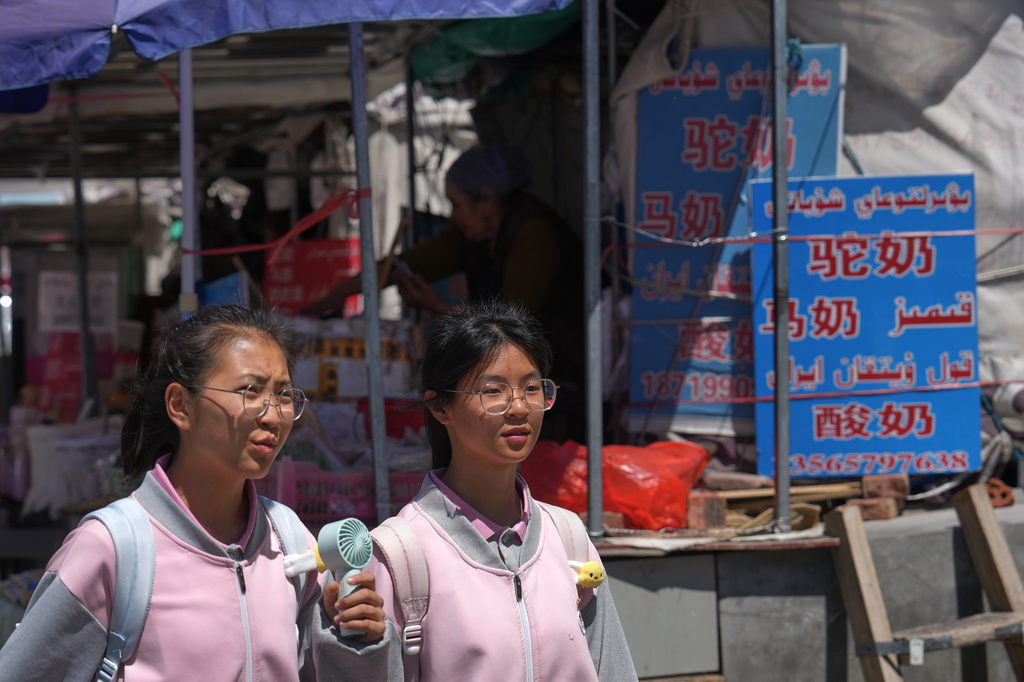 Students walk by a vendor selling variety of milk products at a store along a street in Altay Prefecture, northwest China's Xinjiang Uyghur Autonomous Region, Wednesday, June 10, 2026. (AP Photo/Andy Wong)
