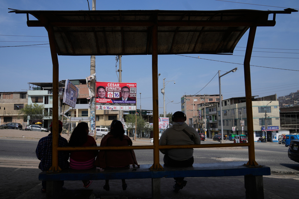 FILE - People sit in a bus station across the street from election campaign signs for presidential and congressional candidates, before the weekend's election in Lima, Peru, Friday, April 10, 2026. (AP Photo/Martin Mejia)