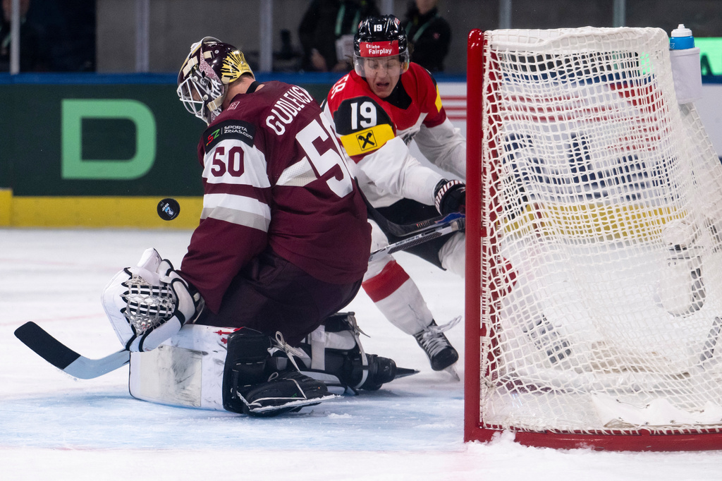 Latvia's goaltender Kristers Gudlevskis, left, and Austria's Vinzenz Rohrer in action during the Men's Ice Hockey World Championship preliminary round game between Latvia and Austria, in Zurich, Switzerland, Tuesday May 19, 2026. (Andreas Becker/Keystone via AP)