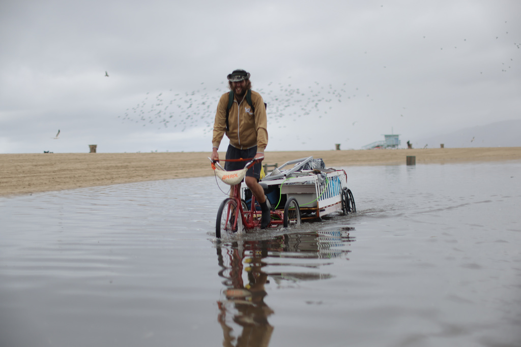 A man bikes along a flooded path after heavy rains Tuesday, Oct. 14, 2025, in Santa Monica, Calif. (AP Photo/Ethan Swope)