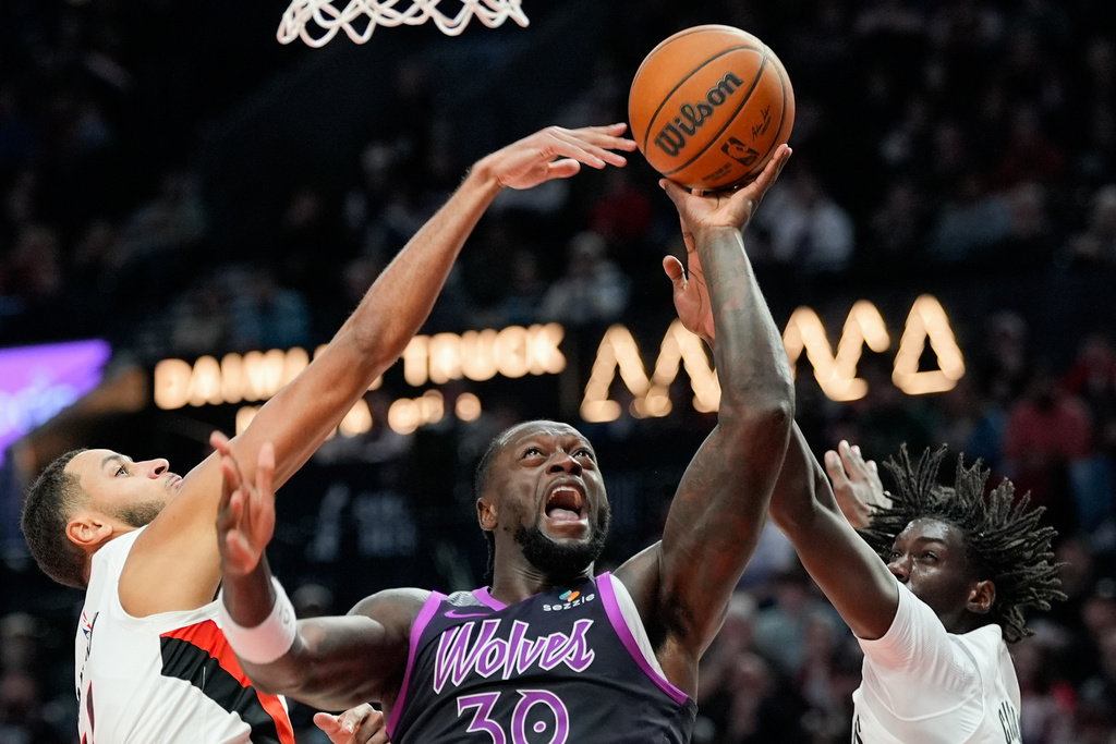 Minnesota Timberwolves forward Julius Randle (30) shoots as Portland Trail Blazers forward Kris Murray, left, and guard Sidy Cissoko, right, defend during the second half of an NBA basketball game Tuesday, Feb. 24, 2026, in Portland, Ore. (AP Photo/Jenny Kane)
