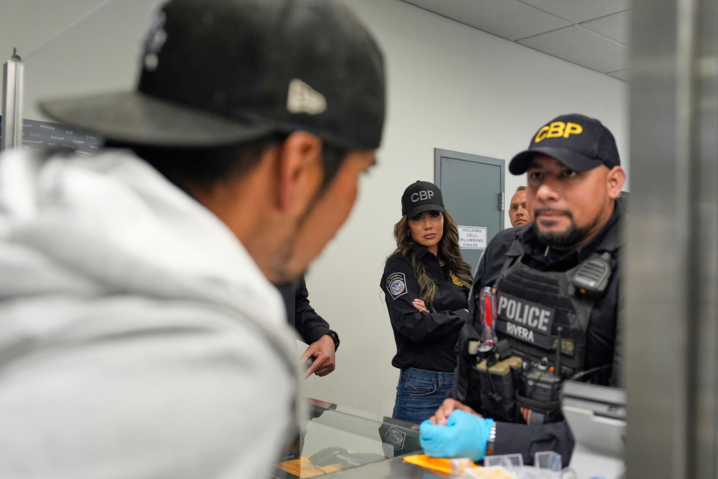 FILE - Homeland Security Secretary Kristi Noem, center, watches as officers speak with a person passing through the San Ysidro Port of Entry, March 16, 2025, in San Diego. (AP Photo/Alex Brandon, File)