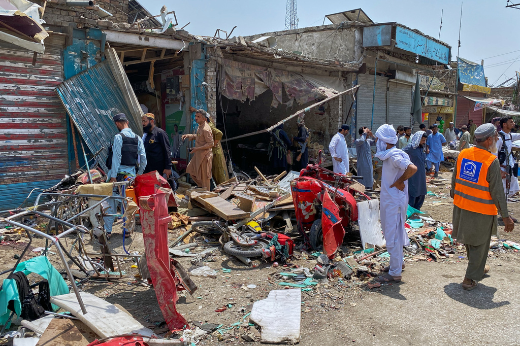 Plainclothes police officers, left, and local residents examine damage at the site of a bomb explosion at a market in Sarai Norag in Lakki Marwat, a district in Pakistan's Khyber Pakhtunkhwa province, Tuesday, May 12, 2026. (AP Photo/Farhat Ullah)