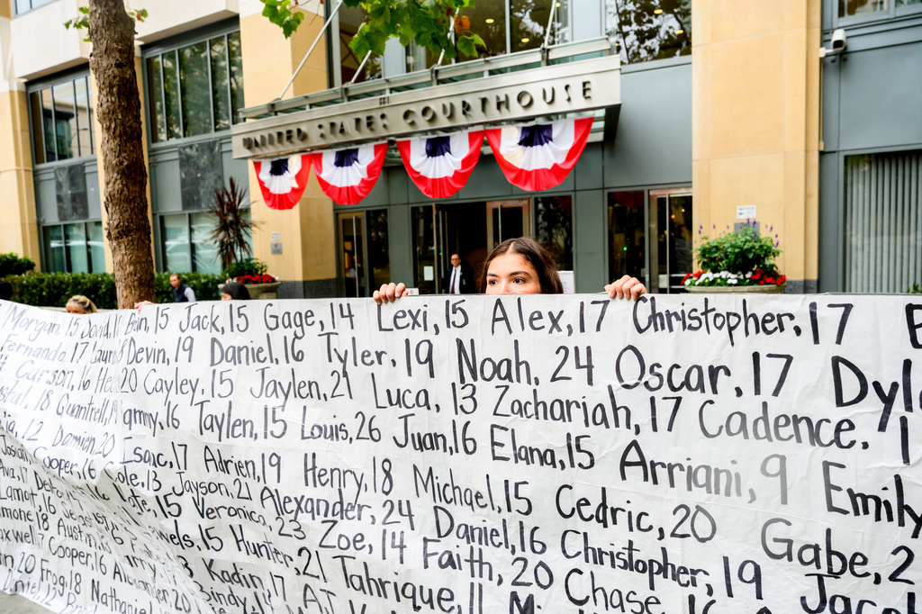 Olivia Konar holds a banner with names of young people who advocates say died as a result of social media outside the Ronald V. Dellums Federal Building and U.S. Courthouse on Tuesday, Aug. 18, 2026, in Oakland, Calif. Her sister Coco Konar died in 2022 when she was 17. (AP Photo/Noah Berger)
