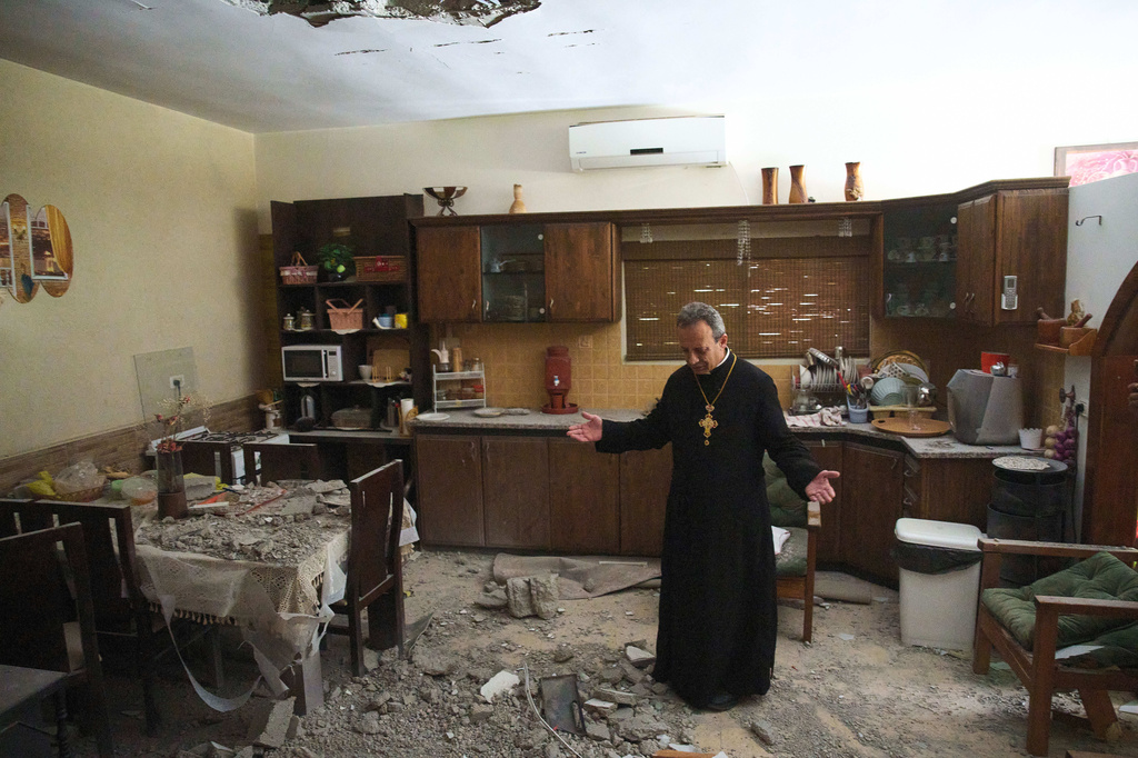 Monsignor Simon Khoury inspects a damaged house following an Iranian missile strike in Shefaram, Israel, Monday, March 30, 2026. (AP Photo/Ariel Schalit)