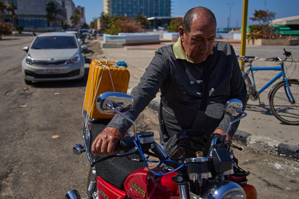 Retiree Jorge Reyes pushes his motorcycle to refuel as it's his turn in line at a gasoline station in Havana, Cuba, Monday, Feb. 16, 2026. (AP Photo/Ramon Espinosa)