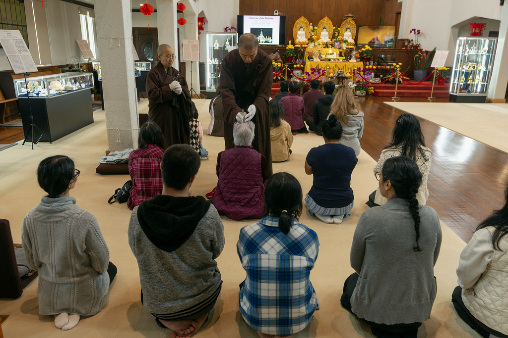 Buddhist resident monks perform a blessing to devotees and visitors at Wei Mountain Temple, in Rosemead, Calif., Saturday, Feb. 17, 2024. (AP Photo/Damian Dovarganes)