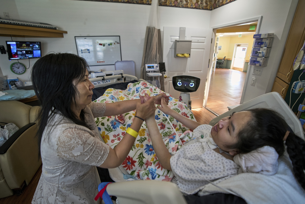 Cara Nguyen with her daughter, Kathy, 18, are visited by Robin the Robot at the HealthBridge Orange Specialty Pediatric Hospital in Orange, Calif., on Friday, Sept. 12, 2025.(AP Photo/Damian Dovarganes)