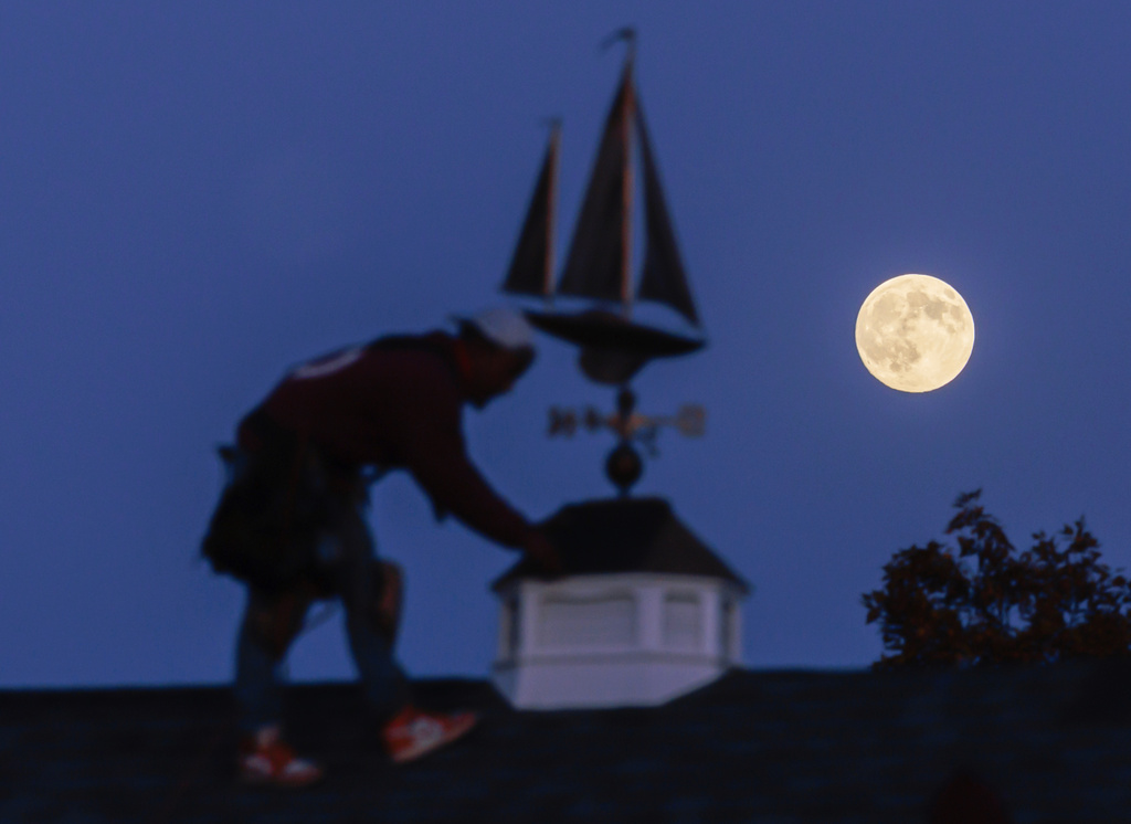 CORRECTS NOT YET A SUPERMOON The moon rises behind a roofing contractor working on a gazebo project in Oconomowoc, Wis., Tuesday, Nov. 4, 2025, before it becomes a Beaver Supermoon early Wednesday morning. (John Hart/Wisconsin State Journal via AP)