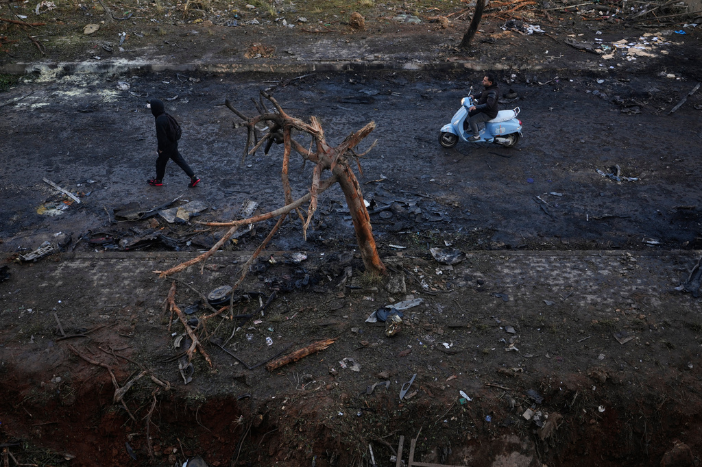 A man rides a scooter past a burned tree and charred debris following an Israeli strike in Beirut, Lebanon, Wednesday, April 1, 2026. (AP Photo/Hassan Ammar)