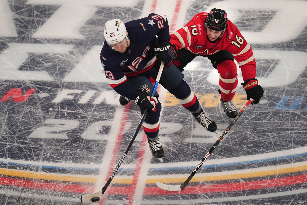 FILE - United States' Adam Fox, left, battles Canada's Mitch Marner for the puck during the first period of the 4 Nations Face-Off championship hockey game, Feb. 20, 2025, in Boston. (AP Photo/Charles Krupa, File)