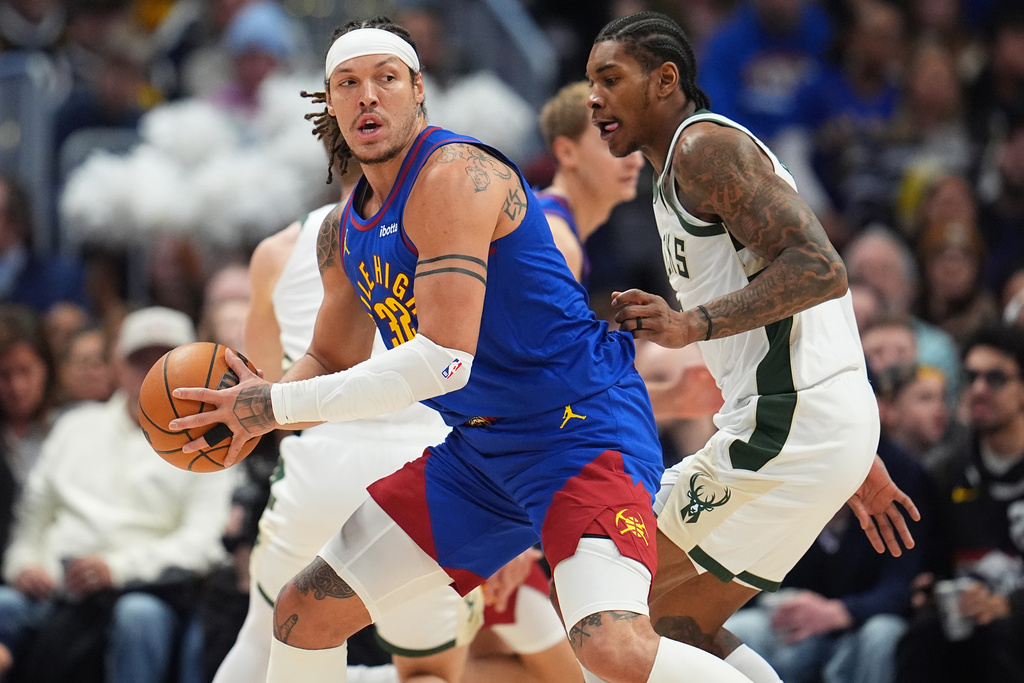 Denver Nuggets forward Aaron Gordon, left, looks to pass the ball as Milwaukee Bucks guard Kevin Porter Jr. defends in the first half of an NBA basketball game, Sunday, Jan. 11, 2026, in Denver. (AP Photo/David Zalubowski)