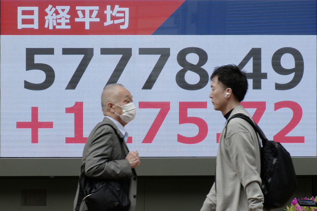 People walk in front of an electronic stock board showing Japan's Nikkei index at a securities firm Tuesday, April 14, 2026, in Tokyo. (AP Photo/Eugene Hoshiko)