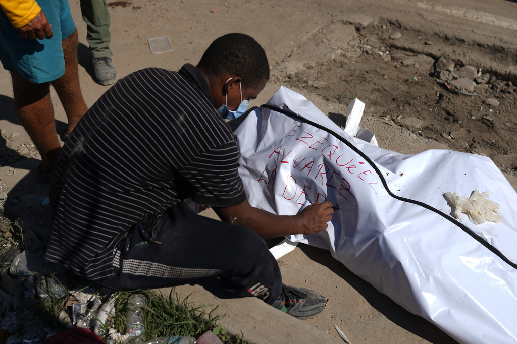Julio Ladera writes the name of his nephew after he found his body in the debris of buildings destroyed by earthquakes in La Guaira, Venezuela, Tuesday, July 7, 2026. (AP Photo/Ariana Cubillos)