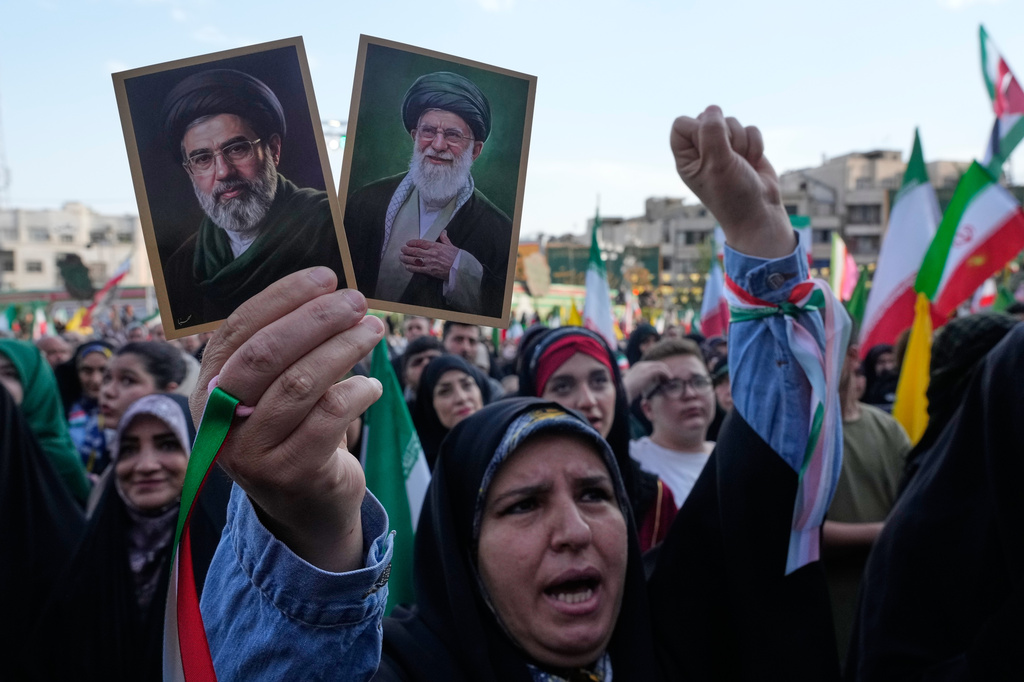 FILE - A woman holds up pictures of the Iranian Supreme Leader Ayatollah Mojtaba Khamenei, left, and his father, the slain Ayatollah Ali Khamenei, during a state-organized rally in Tehran, Iran, April 29, 2026. (AP Photo/Vahid Salemi, File)