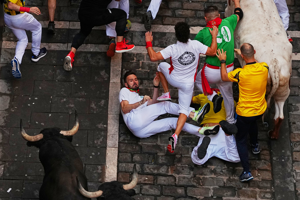 Revelers run alongside Victoriano del Río's fighting bulls during the third running of the bulls at the San Fermín festival in Pamplona, Spain, Thursday, July 9, 2026. (AP Photo/Miguel Oses)