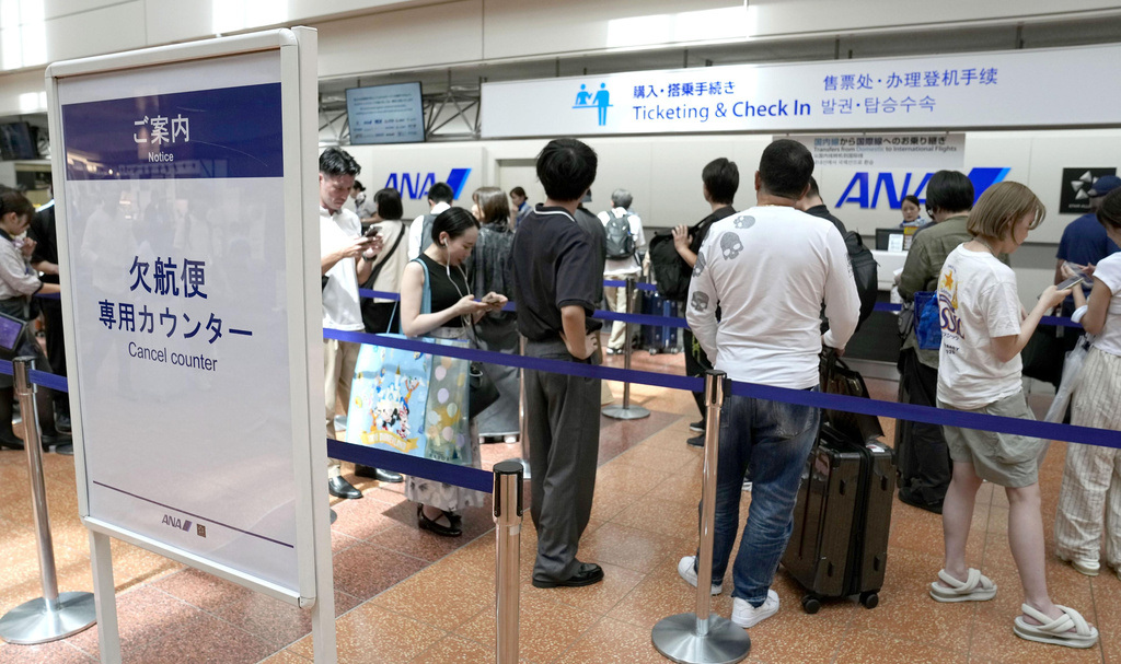 Passengers line up in front of an All Nippon Airways counter at Haneda airport in Tokyo following flight cancellations due to Tropical Storm Chan-hom Tuesday, Aug. 11, 2026. (Katsuya Miyagawa/Kyodo News via AP)
