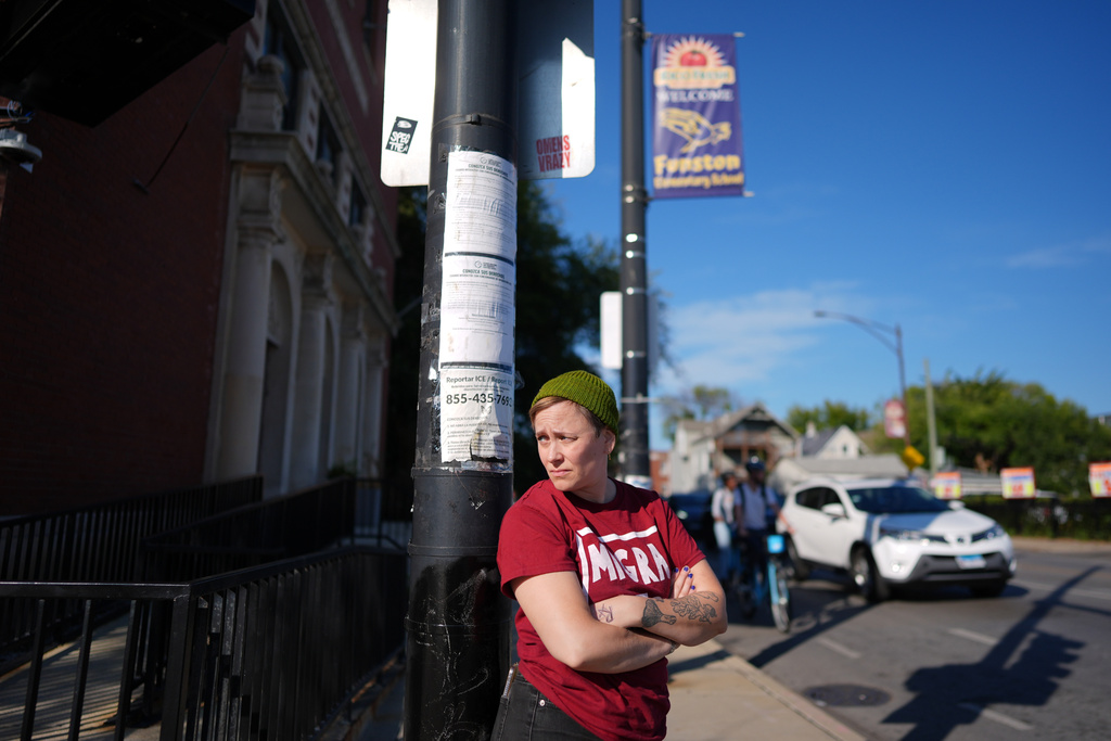 Neighborhood volunteer Amber Young wears a "Migra Watch" tee-shirt as she looks out for federal immigration agents during school dismissal at Funston Elementary School, in Chicago's Logan Square neighborhood, Thursday, Oct. 16, 2025. (AP Photo/Rebecca Blackwell)