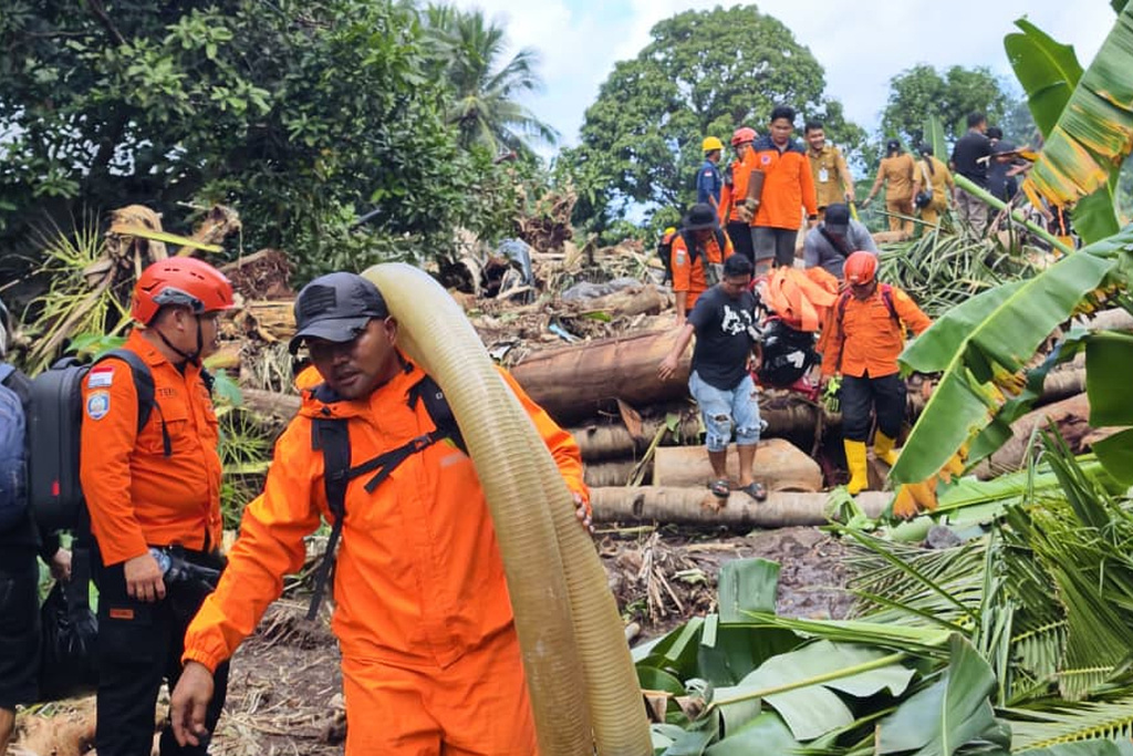In this photo released by the Indonesian National Search and Rescue Agency (BASARNAS) on Tuesday, Jan. 6, 2026, rescuers and villagers search for victims after flash floods hit Sitaro district of North Sulawesi province, Indonesia. (BASARNAS via AP)