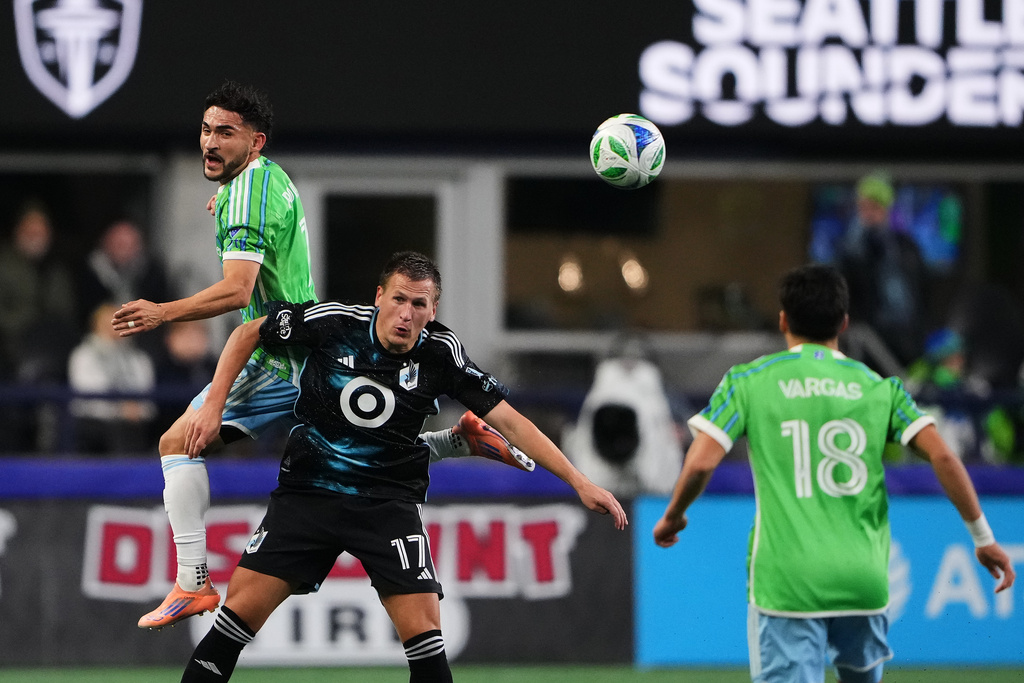 Seattle Sounders midfielder Cristian Roldan, left, goes up for the ball against Minnesota United midfielder Robin Lod (17) during the first half of Game 2 in the first round of MLS soccer's Western Conference playoffs Monday, Nov. 3, 2025, in Seattle. (AP Photo/Lindsey Wasson)