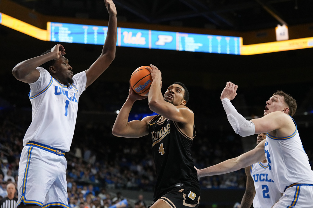 Purdue forward Trey Kaufman-Renn (4) drives to the basket under pressure by UCLA center Xavier Booker (1) and forward Tyler Bilodeau (34) during the first half of an NCAA college basketball game in Los Angeles, Tuesday, Jan. 20, 2026. (AP Photo/Jae C. Hong)