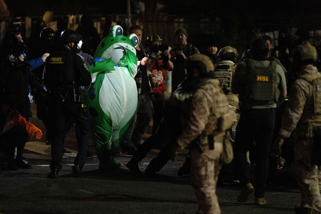 A protester dressed in a costume watches as Department of Homeland Security officers detain a protester outside a U.S. Immigration and Customs Enforcement facility on Thursday, Oct. 2, 2025, in Portland, Ore. (AP Photo/Jenny Kane)