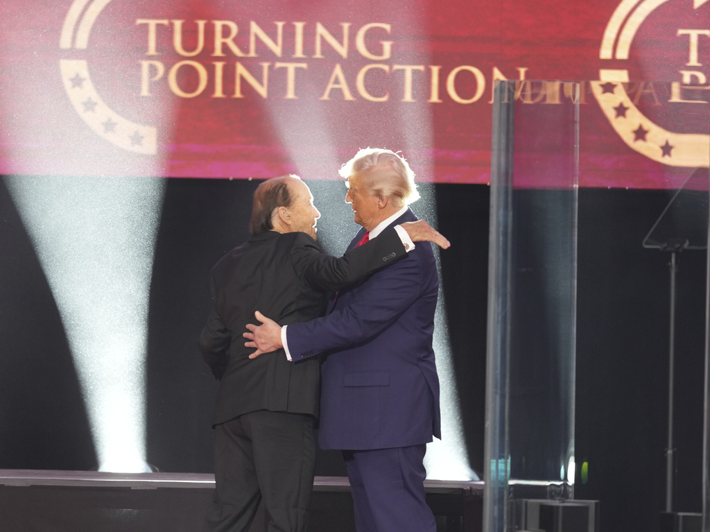 President Donald Trump hugs Lee Greenwood after his performance during a memorial for Charlie Kirk, Sunday, Sept. 21, 2025, at State Farm Stadium in Glendale, Ariz. (AP Photo/Ross D. Franklin)