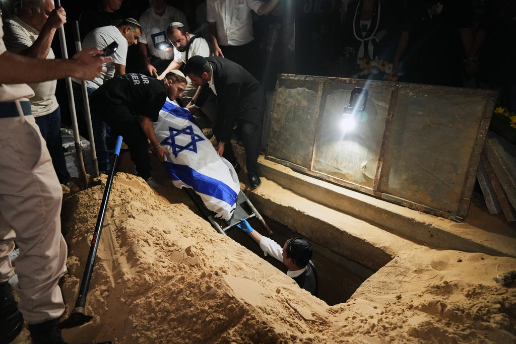 Relatives and friends lower the body of Israeli slain hostage Eitan Levi after his body was returned from Gaza as part of a ceasefire agreement between Israel and Hamas, at Bat Yam cemetery, in Holon, Israel, Thursday, Oct. 16, 2025. (AP Photo/Francisco Seco)