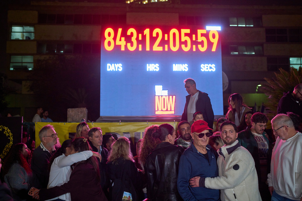 People watch the moment a clock showing the time elapsed since the Hamas attack at Hostages Square stopped in Tel Aviv, Israel, Tuesday, Jan. 27, 2026, one day after the remains of Ran Gvili, the final hostage held in Gaza, were returned. (AP Photo/Ohad Zwigenberg)