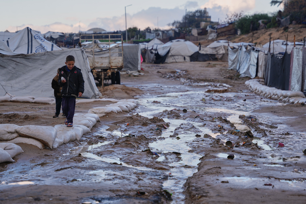 Palestinian children walk past mud puddle after heavy rains in a makeshift camp for displaced people in Zawaida, central Gaza Strip, Wednesday, Dec. 17, 2025. (AP Photo/Abdel Kareem Hana)