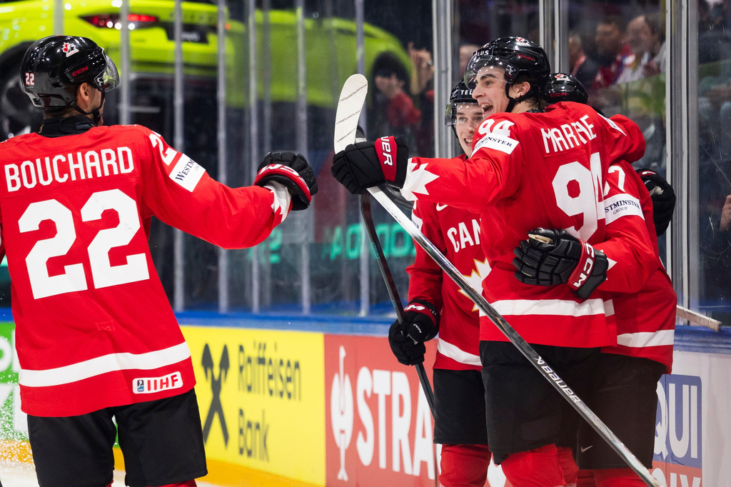Canada's Porter Martone, right, celebrates with his teammates after scoring his side's first goal during the 2026 IIHF Men's Ice Hockey World Championship preliminary round group B game between Canada and Denmark, in Fribourg, Switzerland, Monday, May 18, 2026. (Peter Klaunzer/Keystone via AP)
