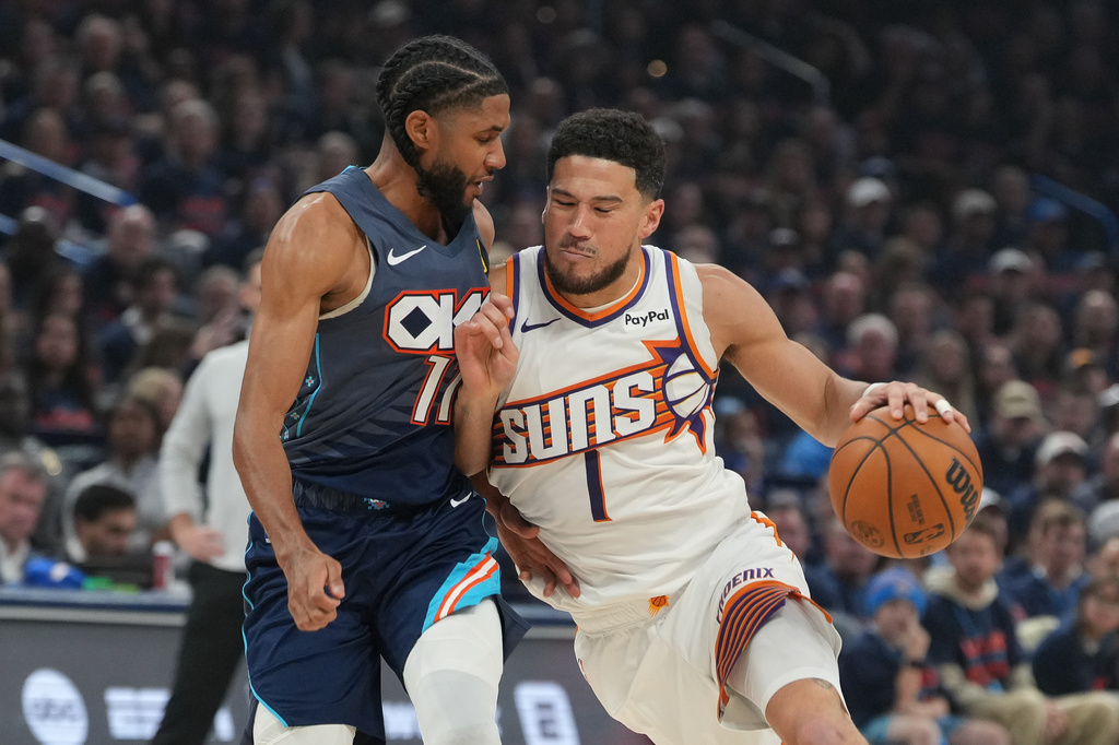 Phoenix Suns guard Devin Booker, right, srives past Oklahoma City Thunder guard Isaiah Joe during the first half in Game 2 of a first-round NBA playoffs basketball series Wednesday, April 22, 2026, in Oklahoma City. (AP Photo/Kyle Phillips)