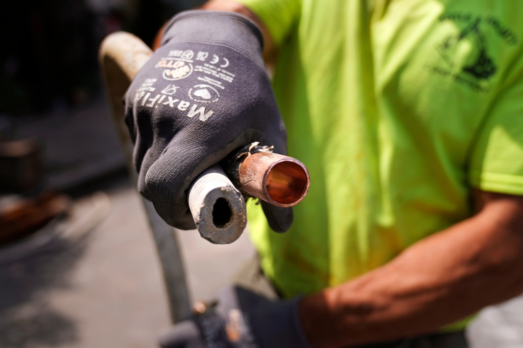 FILE - Richie Nero, of Boyle & Fogarty Construction, shows the the cross section of an original lead, residential water service line, at left, and the replacement copper line, at right, outside a home where service was getting upgraded June 29, 2023, in Providence, R.I. (AP Photo/Charles Krupa, File)