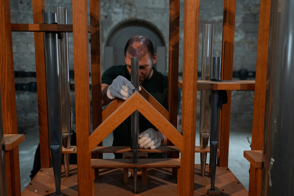 Organ builder Johannes Huefken adjusts a new pipe for a test at the John Cage organ project inside the Buchardi Church in Halberstadt, Germany, July 6, 2026. (AP Photo/Matthias Schrader)