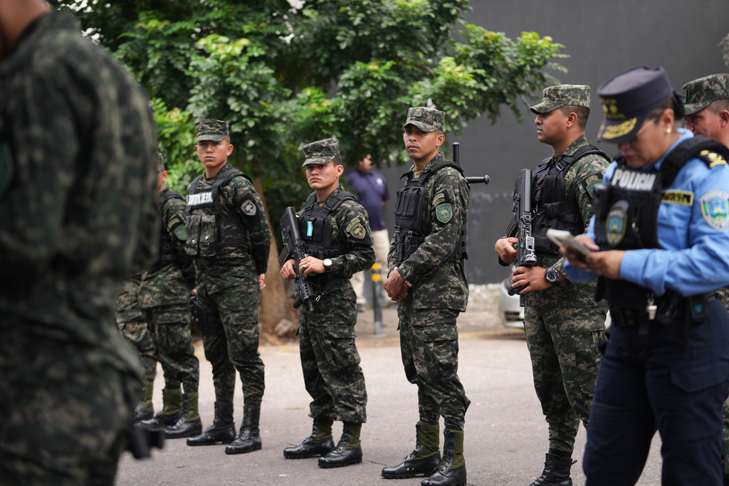 Soldiers stand guard by farmers protesting President Donald Trump's pardon of Honduras' former President Juan Orlando Hernandez in Tegucigalpa, Honduras, Thursday, Dec. 4, 2025. (AP Photo/Moises Castillo)