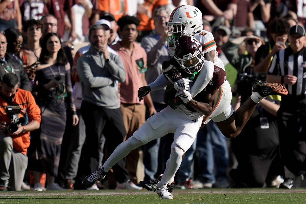 Texas A&M wide receiver Mario Craver has a ball knocked away by Miami defensive back Xavier Lucas during the fourth quarter in the first round of the NCAA College Football Playoff, Saturday, Dec. 20, 2025, in College Station, Texas. (AP Photo/Sam Craft)