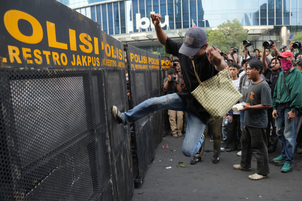 A student protester kicks a police barricade during a rally against a fuel price hike, government inefficient spendings, and military involvement in civilian affairs in Jakarta, Indonesia, Friday, June 12, 2026. (AP Photo/Dita Alangkara)